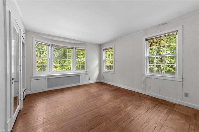 empty room with baseboards, plenty of natural light, hardwood / wood-style flooring, and lofted ceiling
