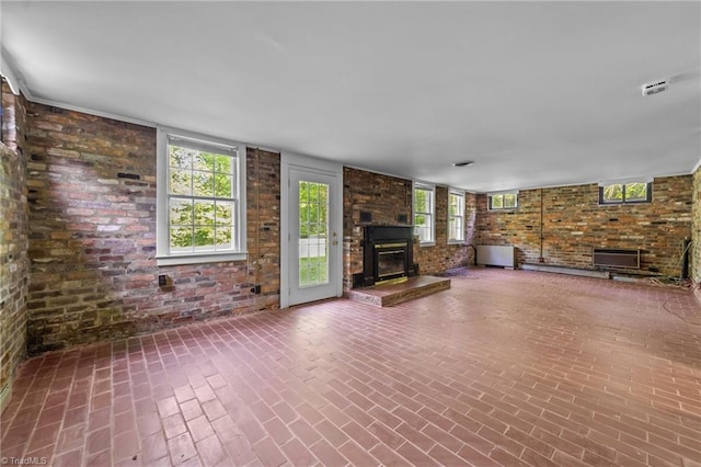unfurnished living room featuring brick wall, brick patterned floor, and a fireplace