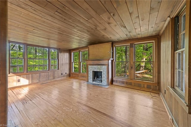 unfurnished living room featuring wood walls, a fireplace, wooden ceiling, and hardwood / wood-style flooring