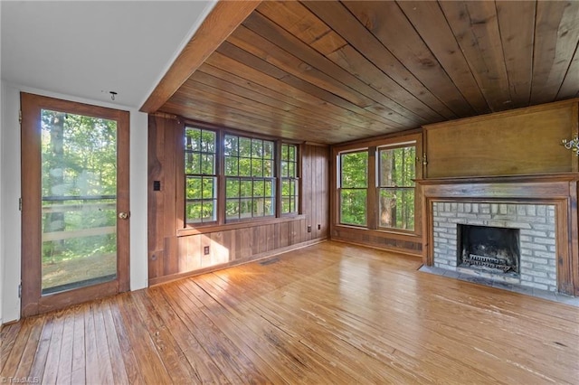 unfurnished living room featuring visible vents, a fireplace, wooden walls, wood ceiling, and hardwood / wood-style flooring