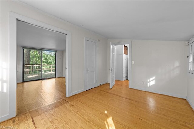 empty room with crown molding, baseboards, and light wood-type flooring