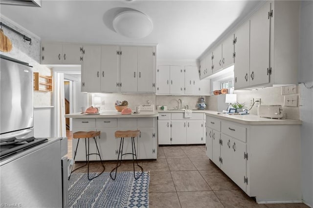 kitchen featuring light countertops, a sink, light tile patterned floors, and white cabinets
