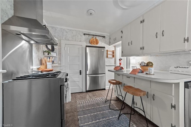 kitchen with appliances with stainless steel finishes, light countertops, extractor fan, white cabinetry, and wallpapered walls
