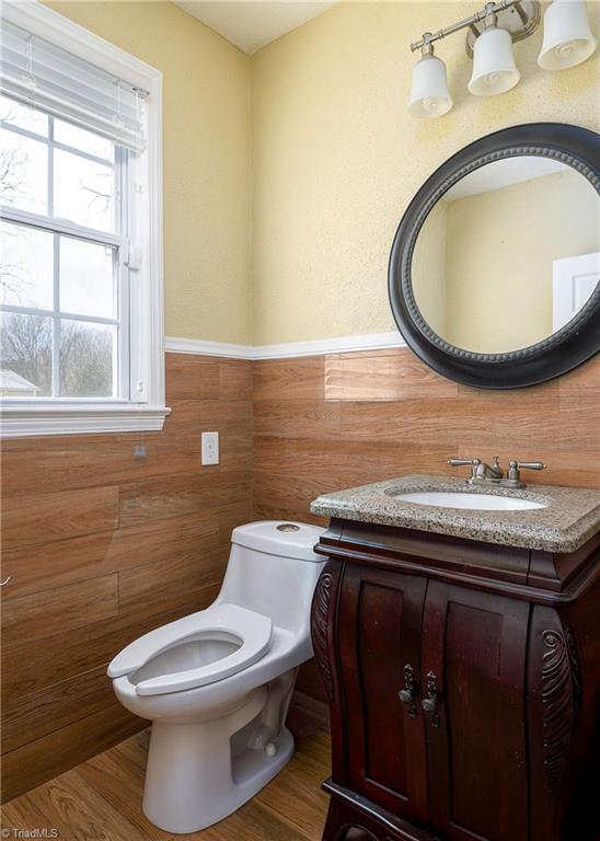 bathroom with toilet, vanity, healthy amount of natural light, and a wainscoted wall
