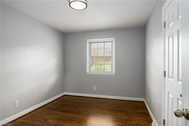 spare room with dark wood finished floors and baseboards