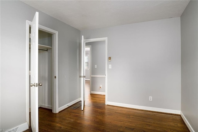unfurnished bedroom featuring wood finished floors, baseboards, and a closet