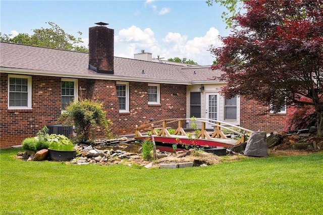 rear view of property with a chimney, brick siding, and a yard