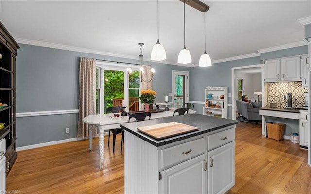573 Doe Run Dr, Kernersville, NC 27284 - kitchen with dark countertops, light wood-style flooring, white cabinets, ornamental molding, and hanging light fixtures