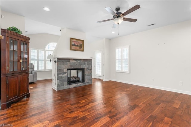 living room featuring vaulted ceiling, visible vents, a fireplace, and wood finished floors