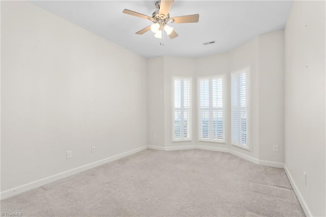 carpeted spare room with ceiling fan, visible vents, and baseboards