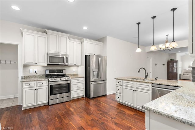 kitchen featuring appliances with stainless steel finishes, white cabinetry, a sink, and backsplash