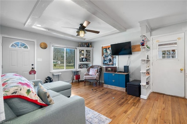 living room with ceiling fan, a tray ceiling, and light hardwood / wood-style flooring