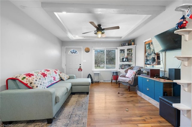 living room featuring a tray ceiling, light hardwood / wood-style floors, and ceiling fan