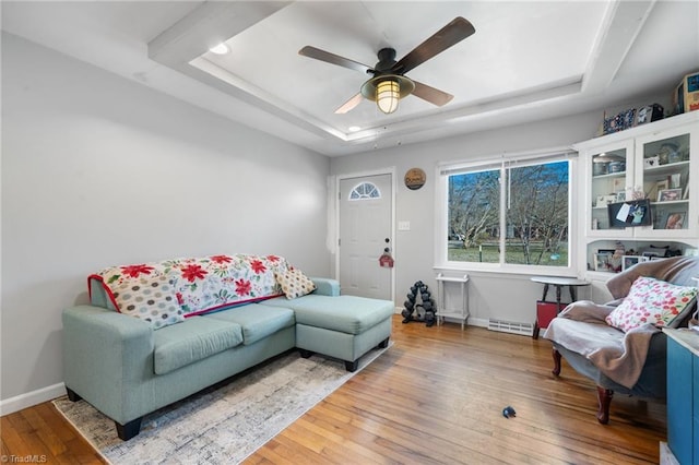 living room featuring hardwood / wood-style flooring, ceiling fan, and a tray ceiling