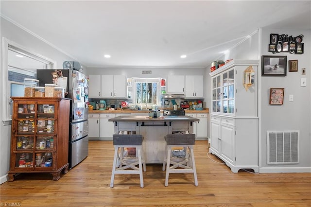 kitchen featuring white cabinetry, a kitchen breakfast bar, a center island, and light wood-type flooring