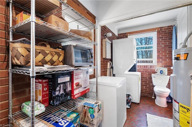 laundry room featuring brick wall and electric water heater