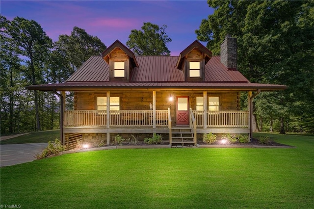 log home with a porch, a yard, a chimney, and metal roof