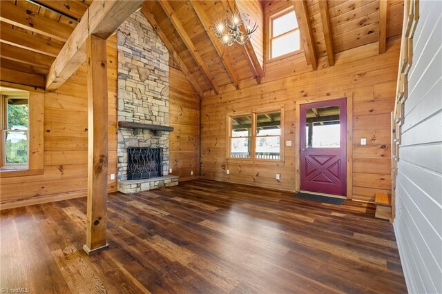 unfurnished living room with wood ceiling, wood finished floors, beamed ceiling, a fireplace, and wooden walls