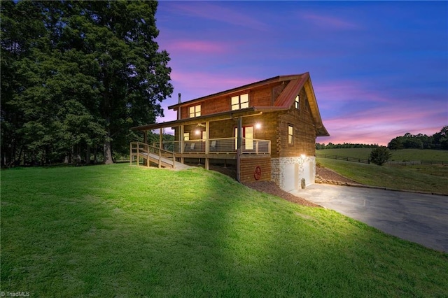 rear view of property featuring concrete driveway, a yard, log siding, and an attached garage