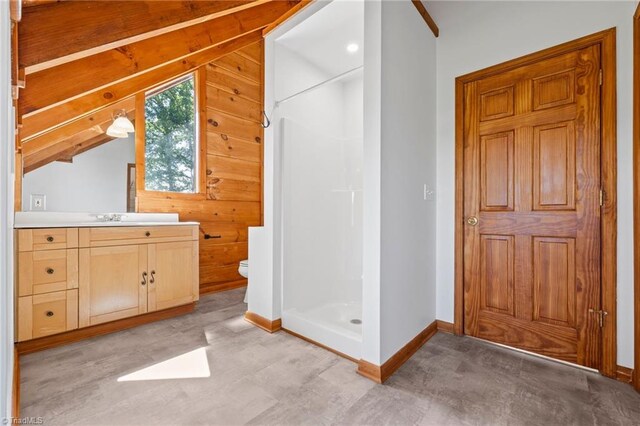 bathroom with vaulted ceiling, a shower stall, vanity, baseboards, and toilet