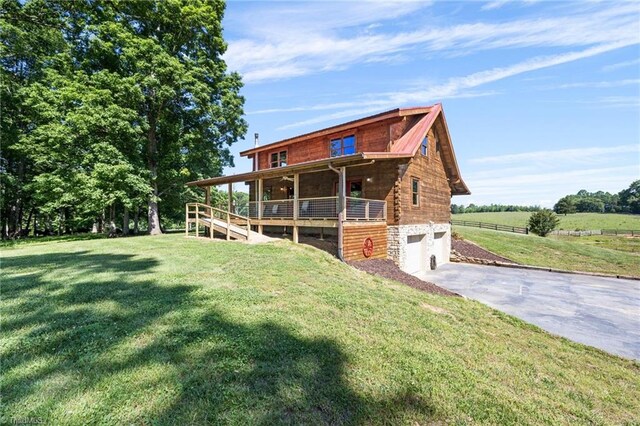 back of property with an attached garage, driveway, a yard, and stone siding