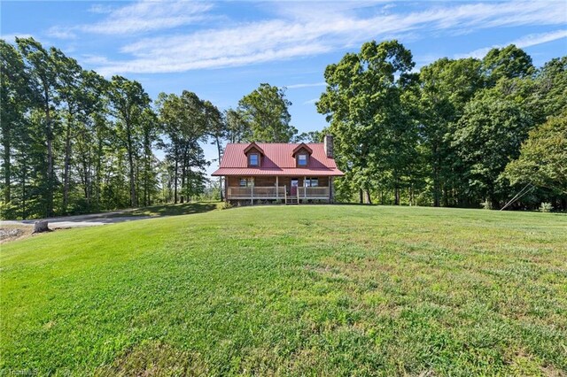 cabin featuring a front yard, metal roof, and a chimney