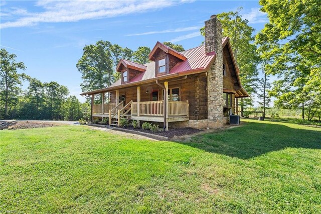 view of front facade with covered porch, a front lawn, metal roof, and a chimney