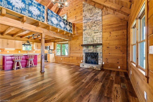 unfurnished living room featuring wood ceiling, dark wood-style flooring, wooden walls, a fireplace, and beamed ceiling