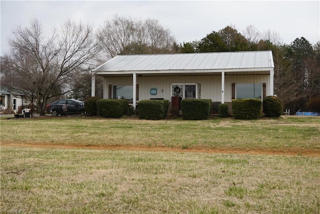 view of front of home with metal roof and a front lawn