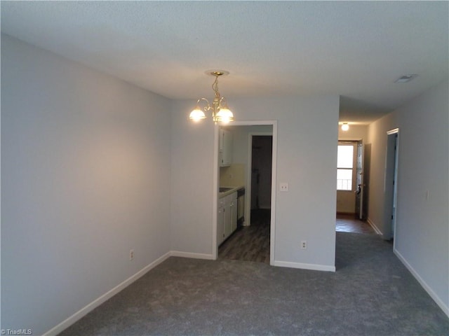 carpeted spare room featuring a chandelier