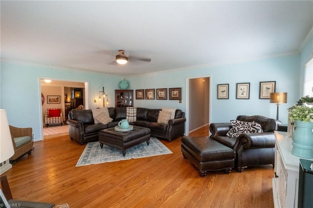 living room featuring light wood finished floors, ceiling fan, and ornamental molding