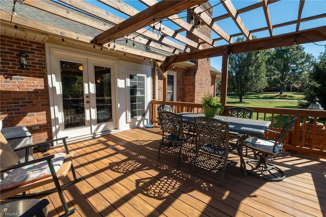 deck featuring outdoor dining area, a lawn, french doors, and a pergola