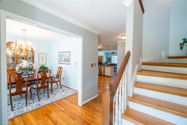 interior space featuring a notable chandelier, ornamental molding, stairway, light wood finished floors, and baseboards