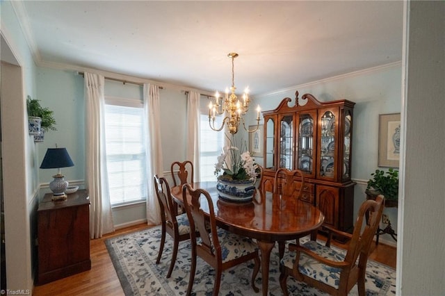 dining room with an inviting chandelier, crown molding, and light wood-type flooring