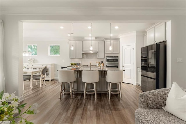 1348 Motsinger Rd, Winston-Salem, NC 27107 - kitchen featuring a breakfast bar, dark wood finished floors, an island with sink, decorative backsplash, and stainless steel refrigerator with ice dispenser