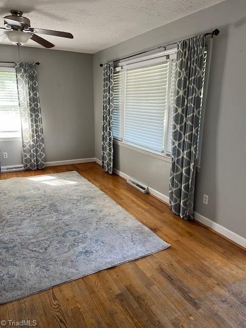 unfurnished room featuring wood-type flooring, a textured ceiling, and ceiling fan