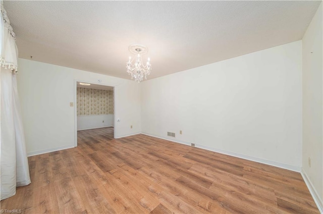 3306 Midkiff Rd, Winston-Salem, NC 27106 - spare room featuring a chandelier, light wood-style floors, and baseboards