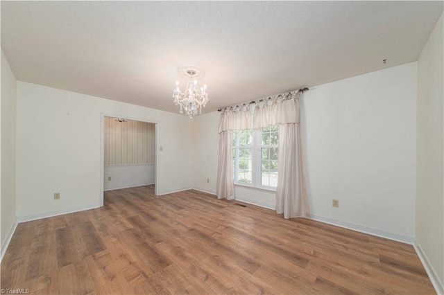 3306 Midkiff Rd, Winston-Salem, NC 27106 - unfurnished room with a chandelier, wood finished floors, baseboards, and a textured ceiling