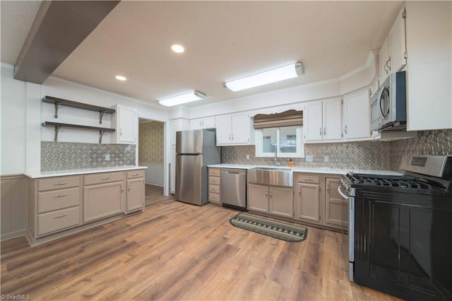 3306 Midkiff Rd, Winston-Salem, NC 27106 - kitchen with appliances with stainless steel finishes, a sink, wood finished floors, light countertops, and crown molding