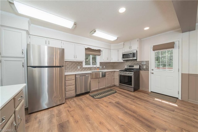 3306 Midkiff Rd, Winston-Salem, NC 27106 - kitchen with appliances with stainless steel finishes, a sink, crown molding, light wood-type flooring, and light countertops