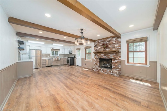 3306 Midkiff Rd, Winston-Salem, NC 27106 - unfurnished living room featuring light wood finished floors, beamed ceiling, plenty of natural light, a fireplace, and a decorative wall