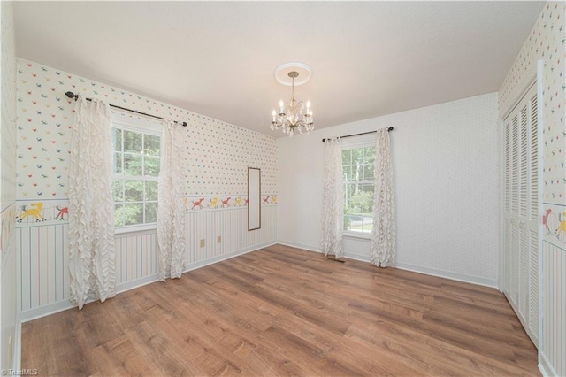 3306 Midkiff Rd, Winston-Salem, NC 27106 - unfurnished dining area with wallpapered walls, a chandelier, wood finished floors, healthy amount of natural light, and baseboards