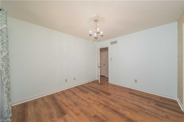 3306 Midkiff Rd, Winston-Salem, NC 27106 - unfurnished room featuring a chandelier, wood finished floors, and baseboards