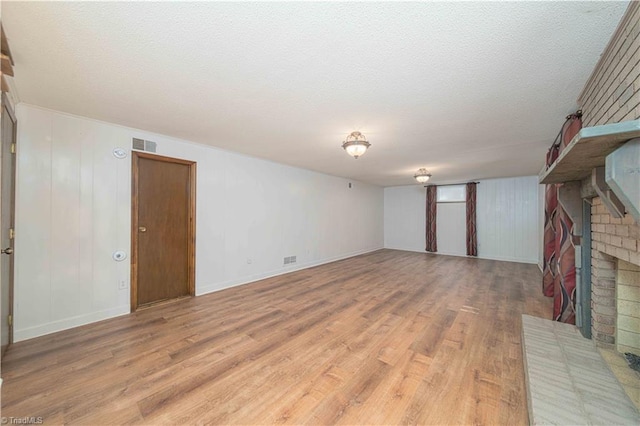 3306 Midkiff Rd, Winston-Salem, NC 27106 - unfurnished living room with light wood-type flooring, a fireplace, a textured ceiling, and baseboards