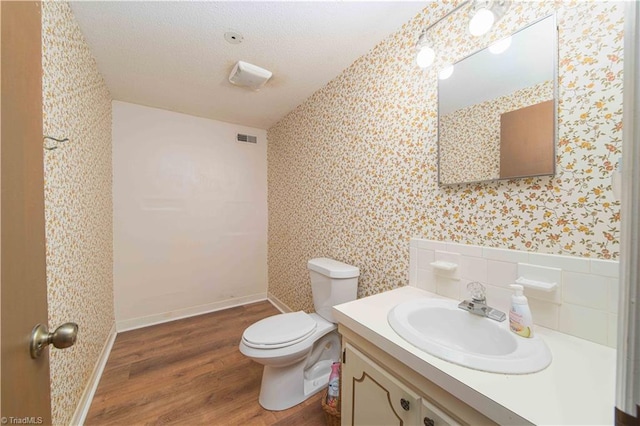 3306 Midkiff Rd, Winston-Salem, NC 27106 - bathroom featuring wallpapered walls, wood finished floors, vanity, toilet, and a textured ceiling