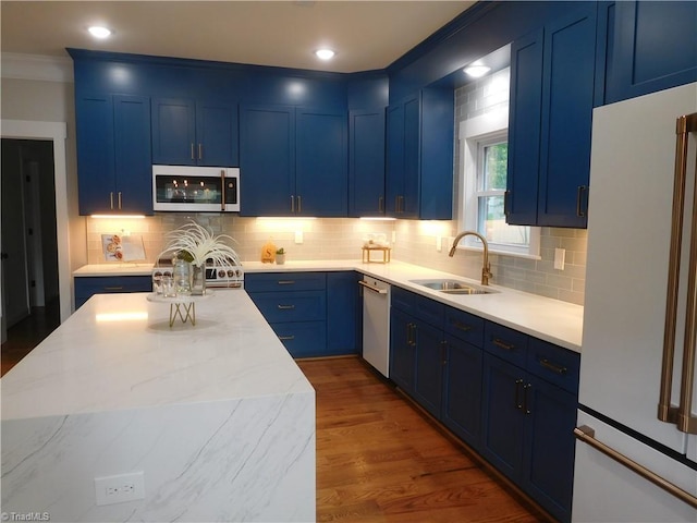 kitchen featuring backsplash, white appliances, blue cabinets, and a sink