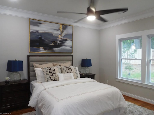 bedroom with visible vents, ornamental molding, a ceiling fan, wood finished floors, and baseboards