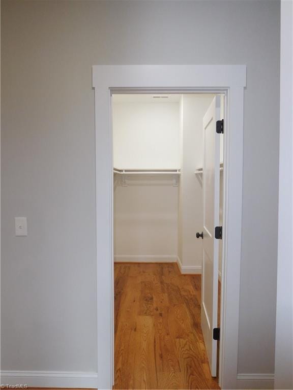 walk in closet with wood finished floors