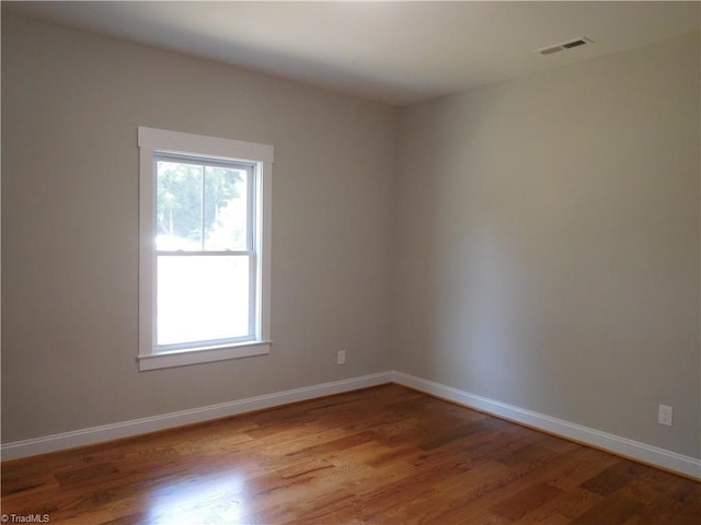 empty room featuring visible vents, baseboards, and wood finished floors