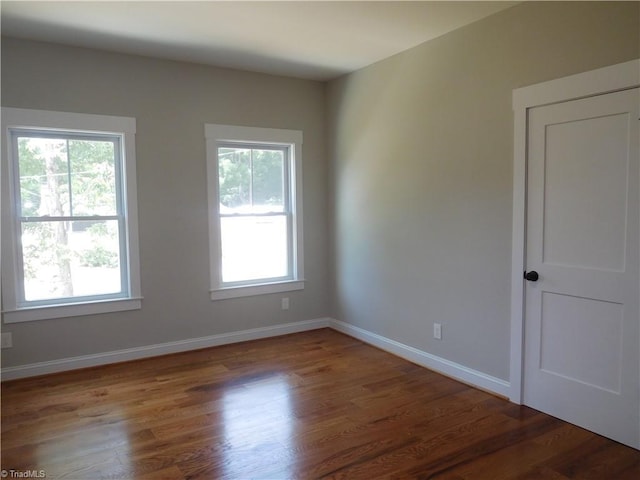 unfurnished room with baseboards, a healthy amount of sunlight, and wood finished floors